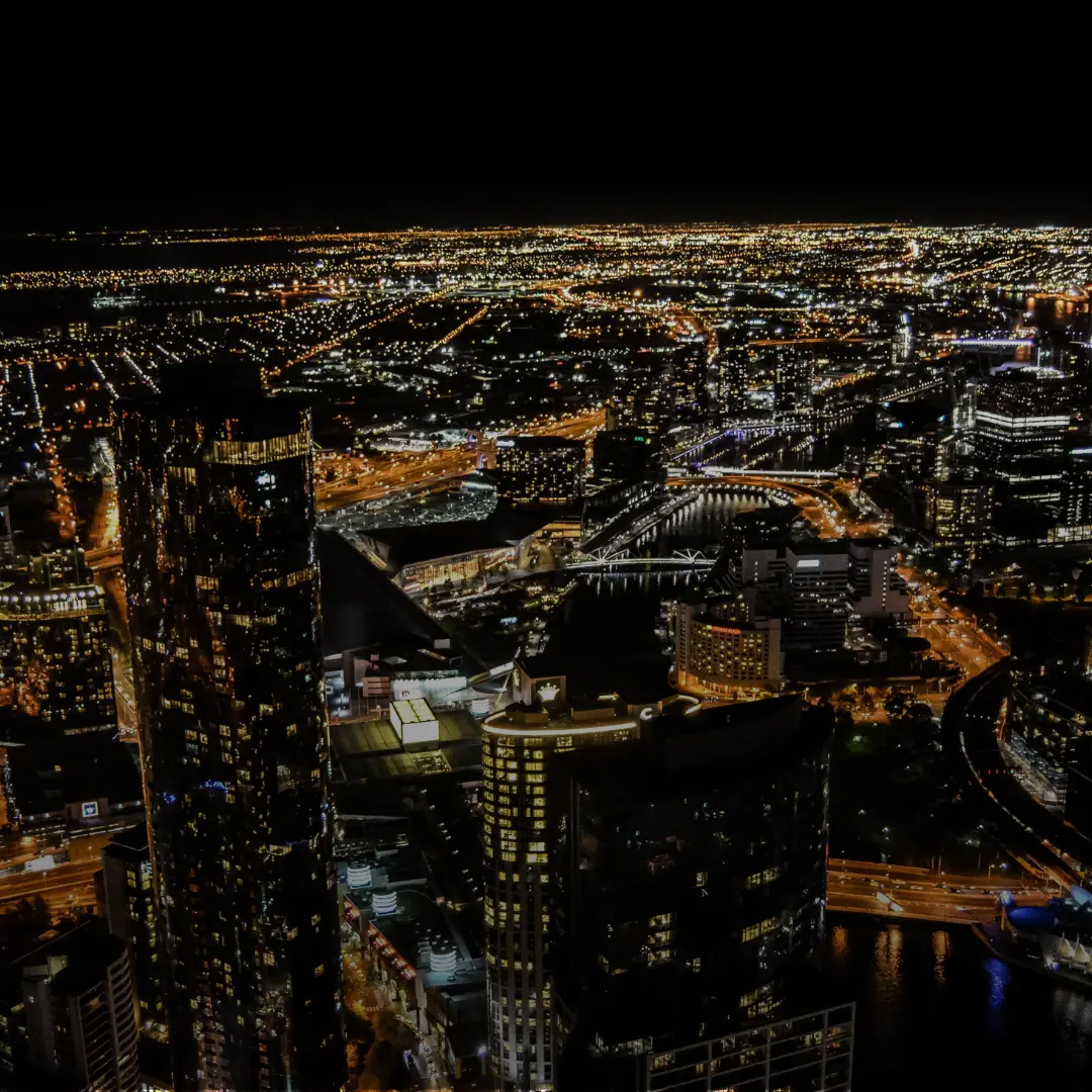 A photo of the Melbourne skyline lit up with yellow neon lights at night